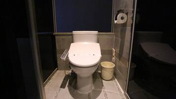 Ein kleines, modernes Badezimmer mit Toilette, Mülleimer und Toilettenpapierhalter an der Wand.