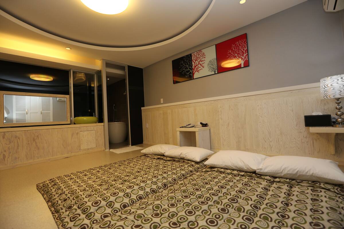 Ein modernes Schlafzimmer mit einem großen Bett, einem Einbauschrank, einem Nachttisch und einem Wandbild.