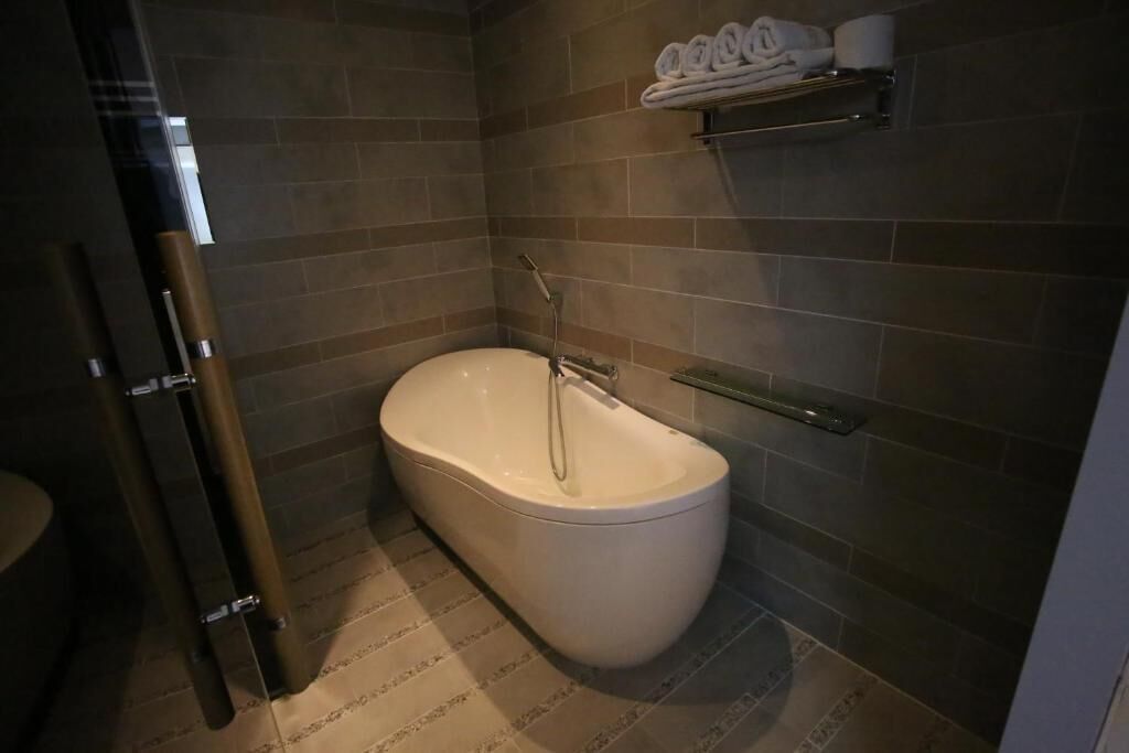 A modern bathroom with a freestanding bathtub, a towel rack, and a toilet.