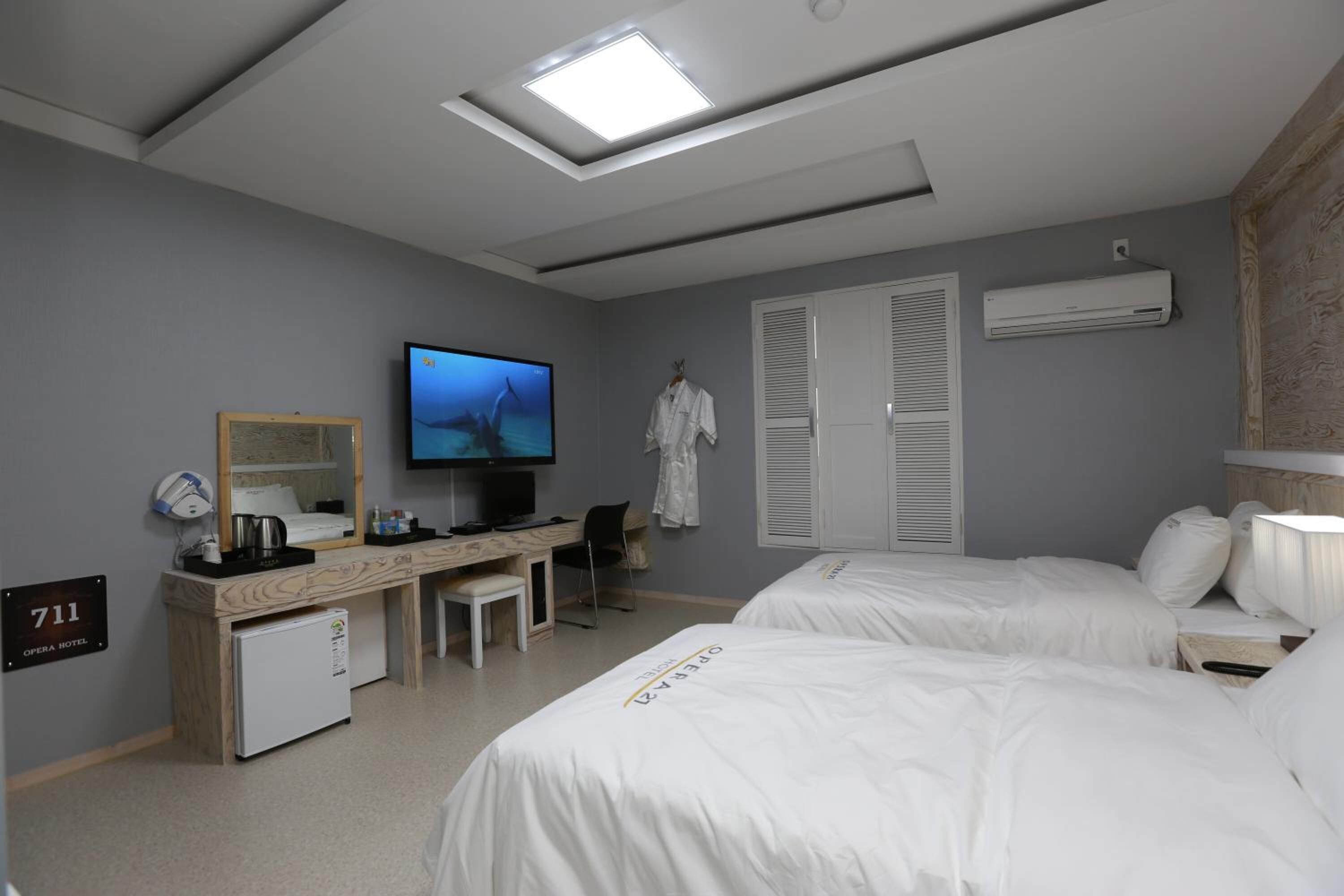 Een hotelkamer met twee bedden, een bureau met een computer, een televisie en een minibar.