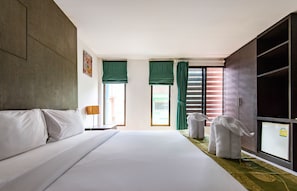 A hotel room with a large bed, a wardrobe, a desk with a lamp, and a view of the outside. - BGW Phuket - Hostel (Patong)