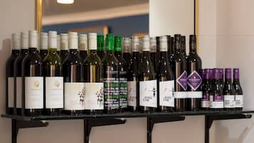 Una estantería para vinos con diversas botellas, incluyendo marcas como AlKooM y Fifth Leg.