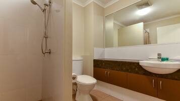 Une salle de bain équipée d’une douche, de toilettes, d’un lavabo et d’un meuble de rangement.