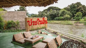 Un área de estar al aire libre con techo de paja, mobiliario tejido y un letrero que dice "Treehouse".