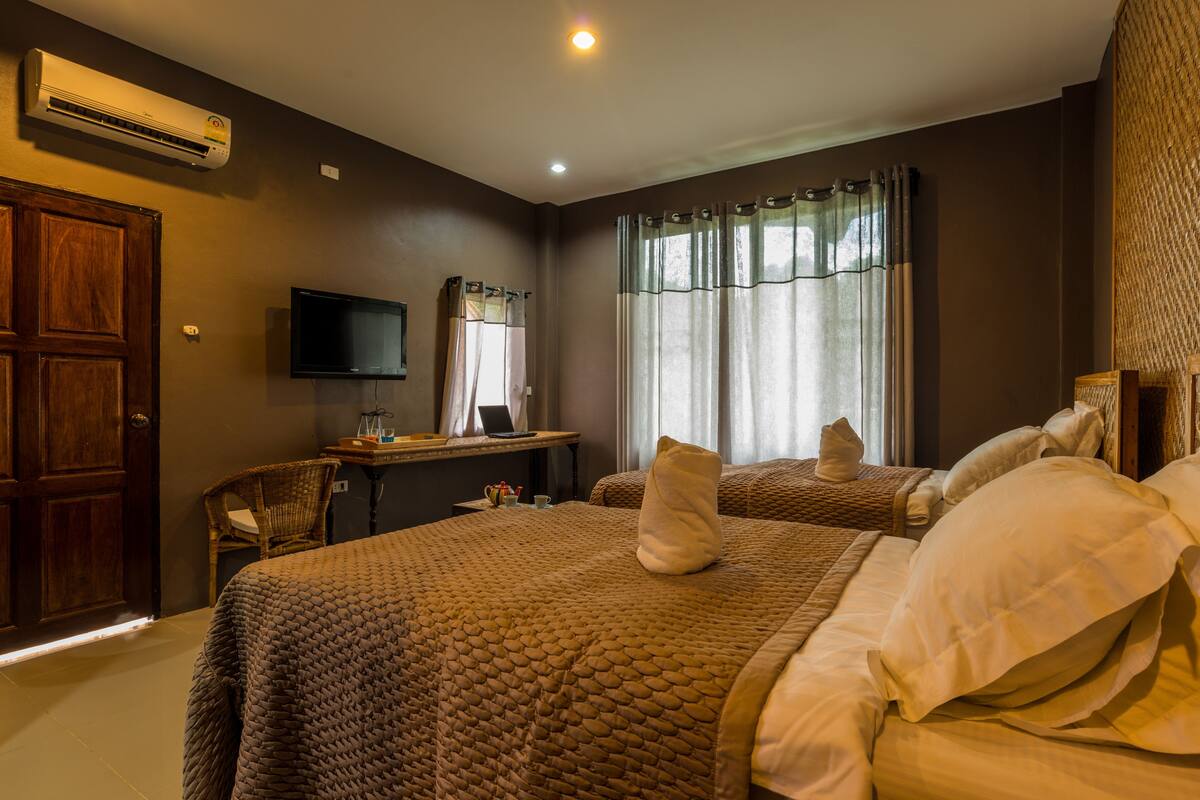 Una habitación de hotel con una cama grande, un escritorio con computadora, un televisor y una ventana con cortinas.