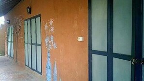Un edificio con un largo pasillo, ventanas amplias y una puerta con manija de metal.