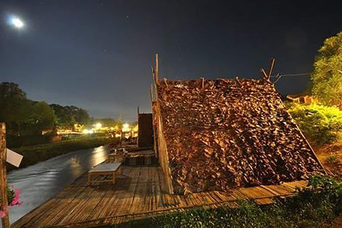 Una estructura de madera con techo inclinado, posiblemente un pabellón o cobertizo, ubicada sobre una plataforma de madera a orillas de un río.