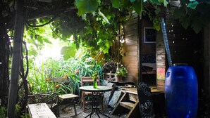 A rustic outdoor seating area with a wooden table and chairs, surrounded by lush greenery and a wooden structure. - B&B Hostel (Punta del Este)