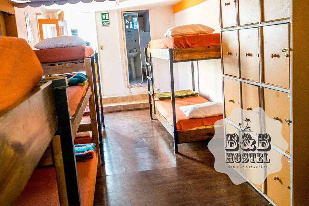 A hostel room with bunk beds, a wooden wardrobe, and a visible exit door.