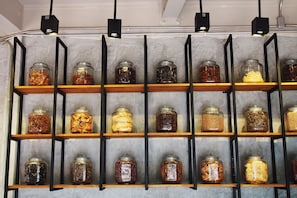 A wall of glass jars with various contents, organized on wooden shelves with black metal frames.