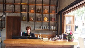 A bar area with a wooden counter, shelves with jars, and hanging lights. - Bangkok Story - Hostel (Bangkok)