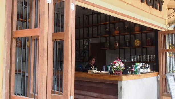 The exterior of Bangkok Story, featuring a wooden facade, a counter with various items, and a tiled floor. - Bangkok Story - Hostel (Bangkok)
