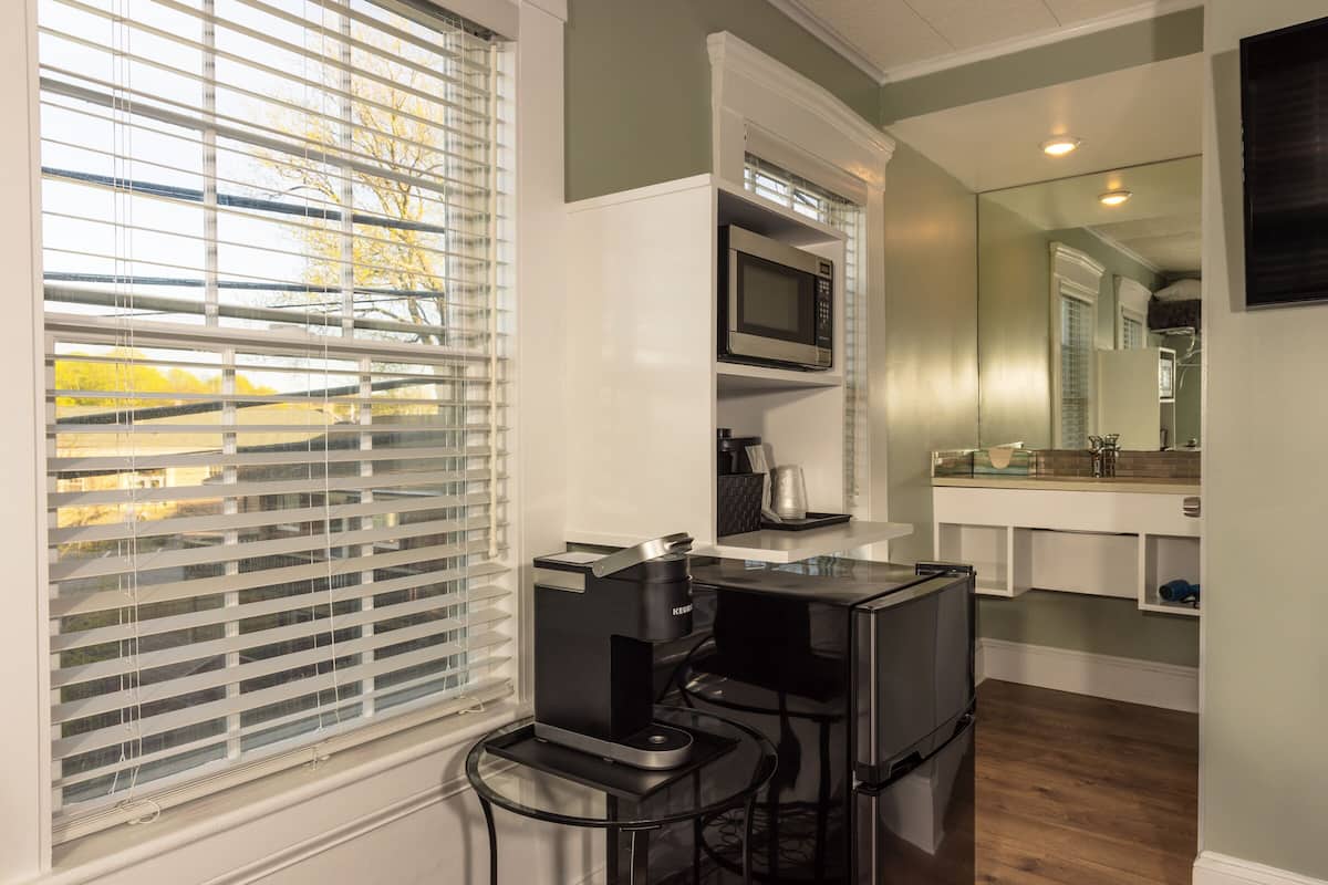 A modern kitchen with a built-in microwave, coffee maker, and a large mirror above the sink.