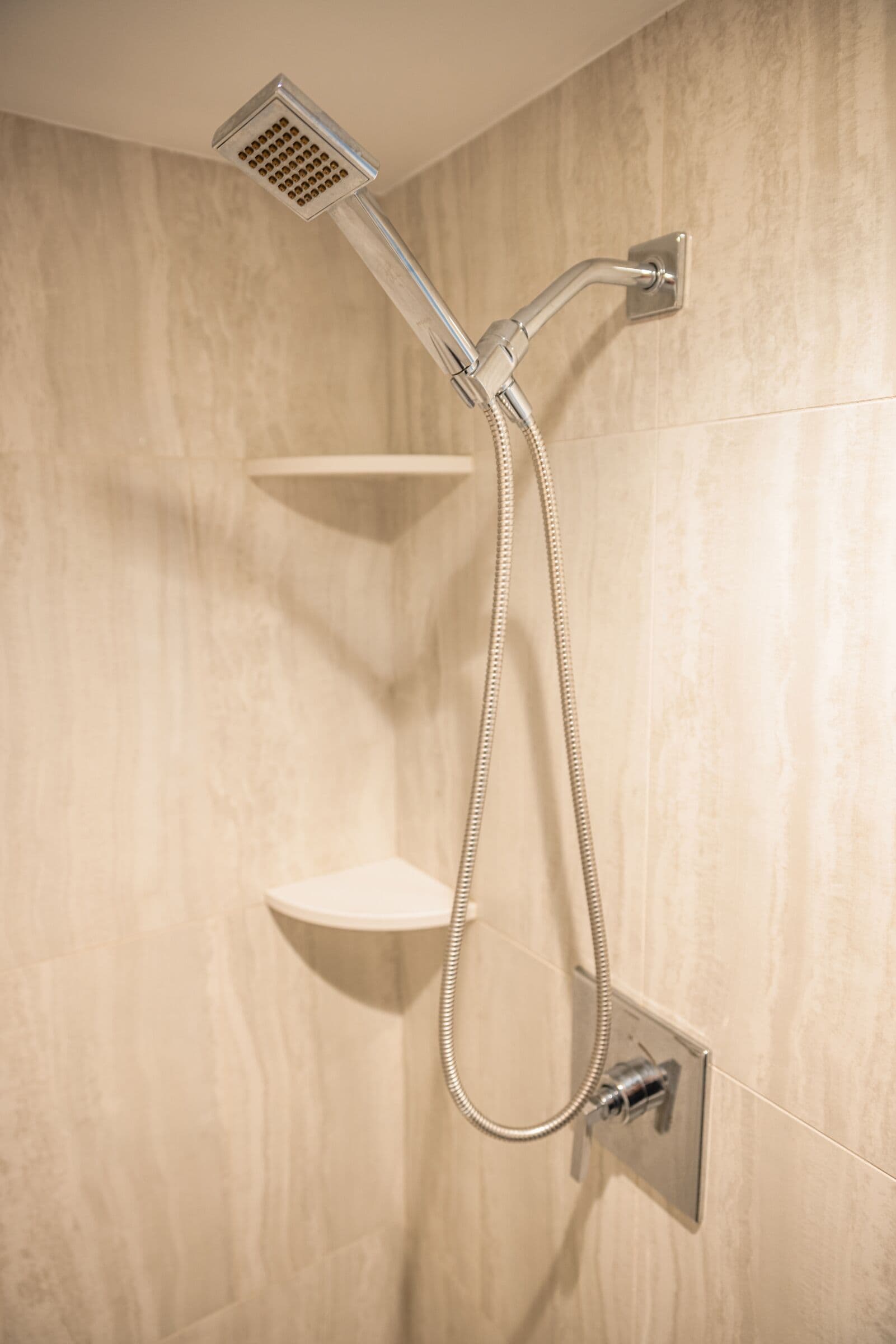 A shower with a handheld showerhead and a handheld hose.