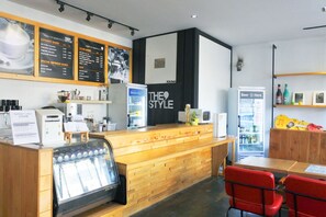 A coffee shop interior with a wooden counter, espresso machine, and menu boards. - The Style Capsule Guesthouse - Hostel (Daegu)