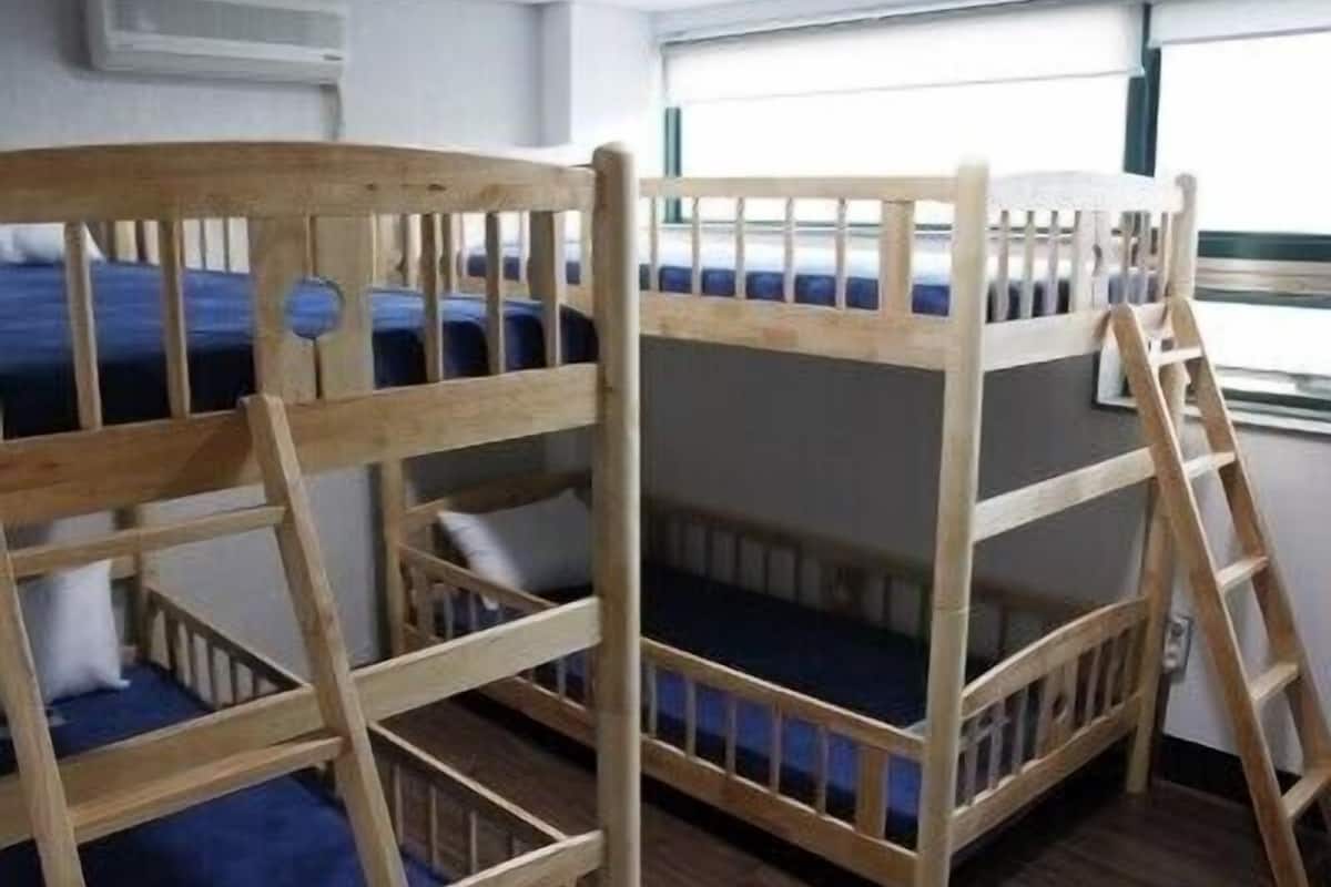 A bunk bed room with a ladder, a window, and an air conditioning unit.