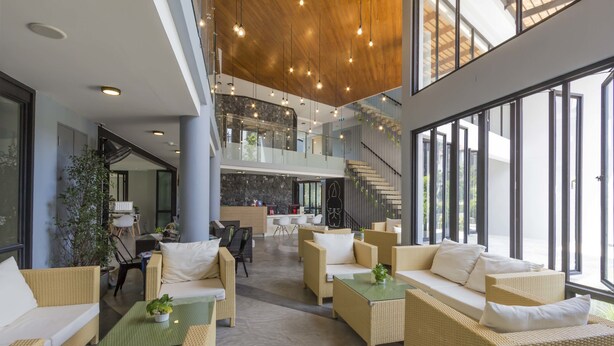 A spacious lobby with wicker furniture, a staircase, and large windows.