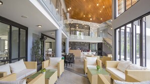 A spacious indoor area with wicker furniture, a reception desk, and a staircase leading to an upper level.