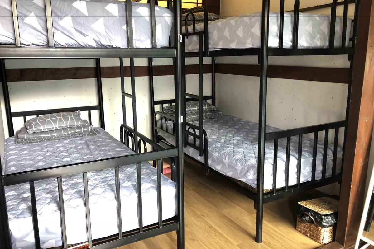 A bunk bed room with three levels, wooden flooring, and a small wicker basket under the lower bunk.