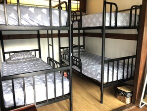 A bunk bed room with three levels, wooden flooring, and a small wicker basket under the lower bunk.