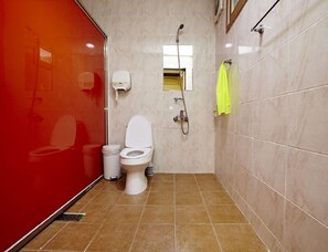 A bathroom with a toilet, a shower, and a red wall.