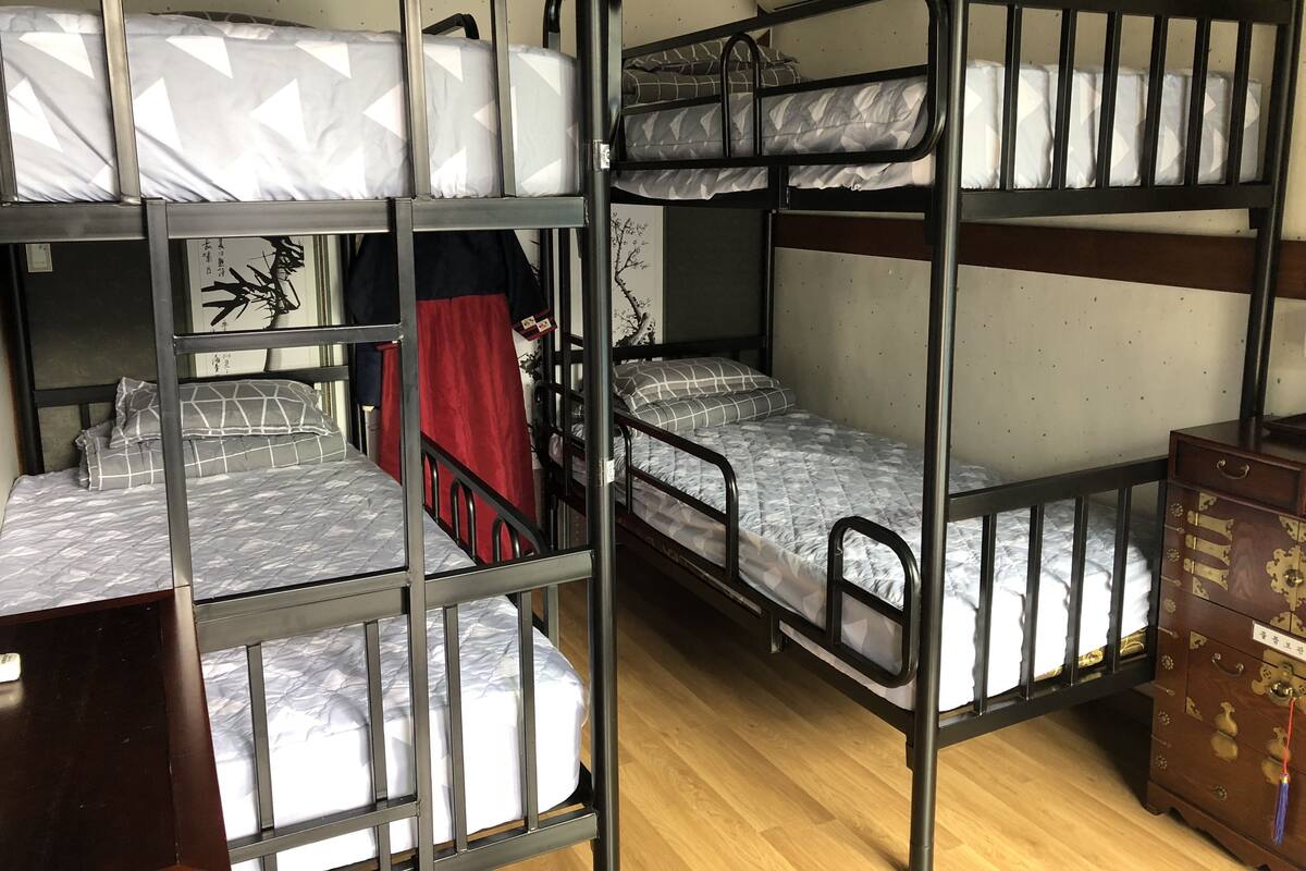 A bunk bed room with a wooden dresser and an air conditioning unit.