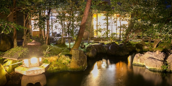 A tranquil garden with a pond, rocks, and a traditional Japanese lantern.