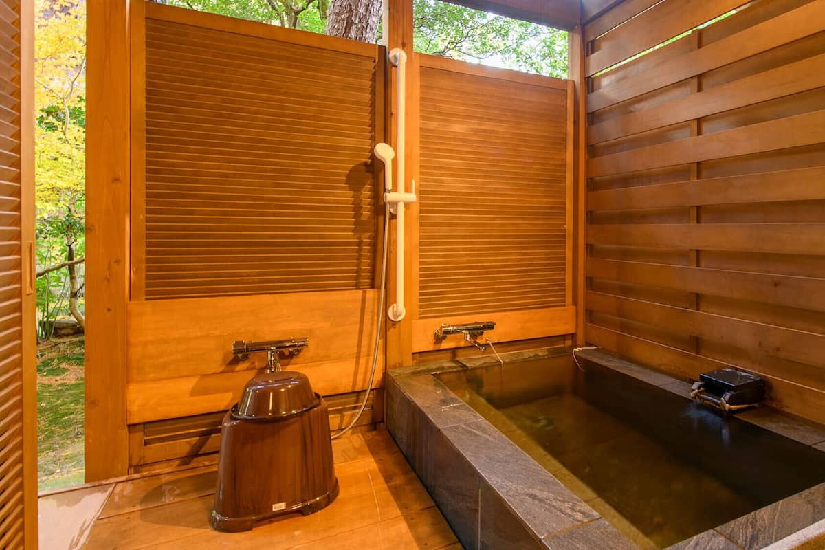 A wooden spa with two sliding doors, a hot tub, and a water pump.