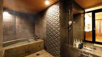 A modern bathroom with a stone wall, a bathtub, and a shower area.