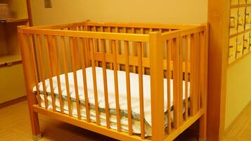 A wooden crib with a white mattress in a room with yellow walls and a wooden floor.