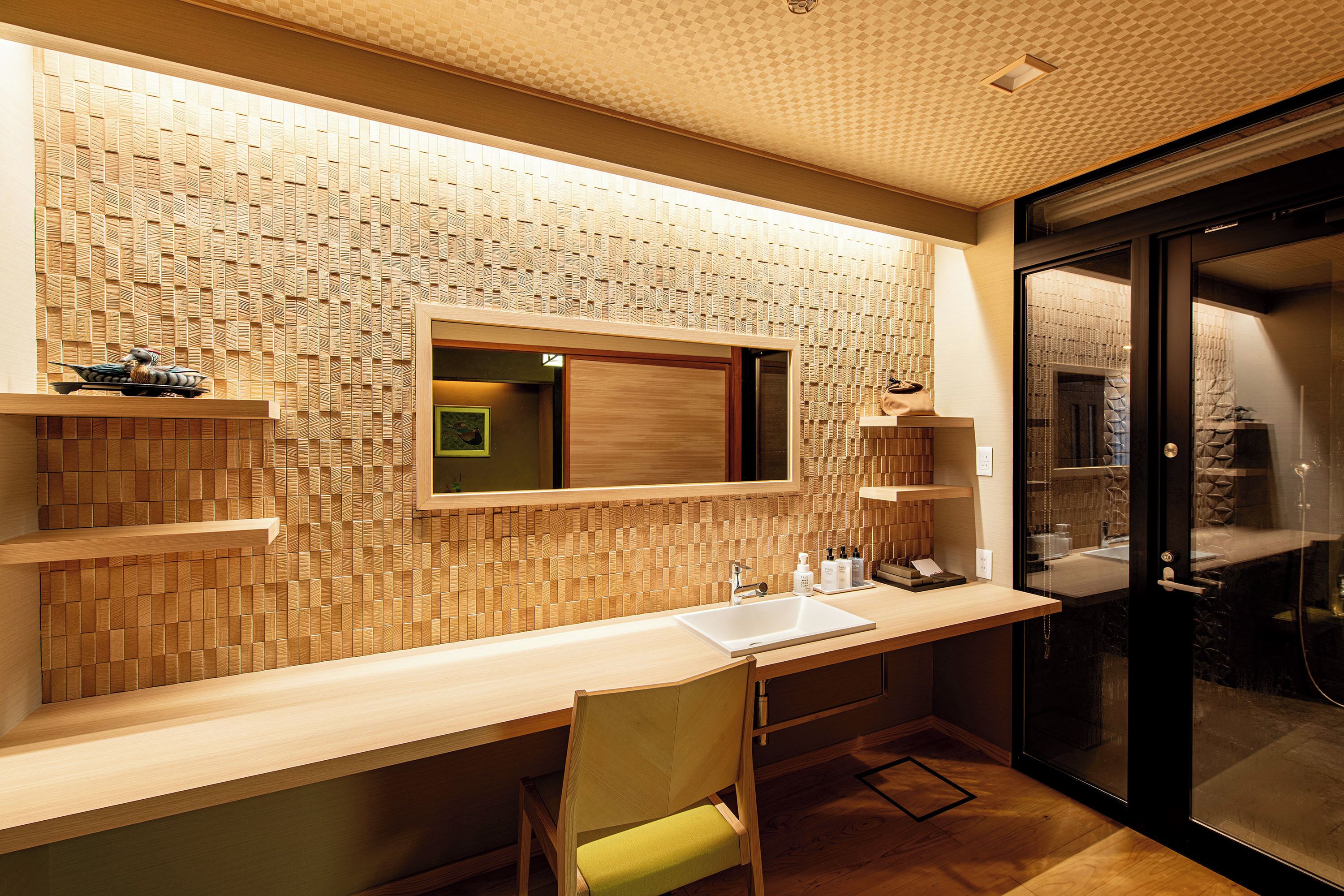 A modern bathroom with a wooden mosaic wall, a sink with a mirror, and a shower area.