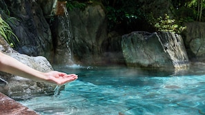 A hand reaching into clear water with a rocky background. - Houshi (Komatsu)