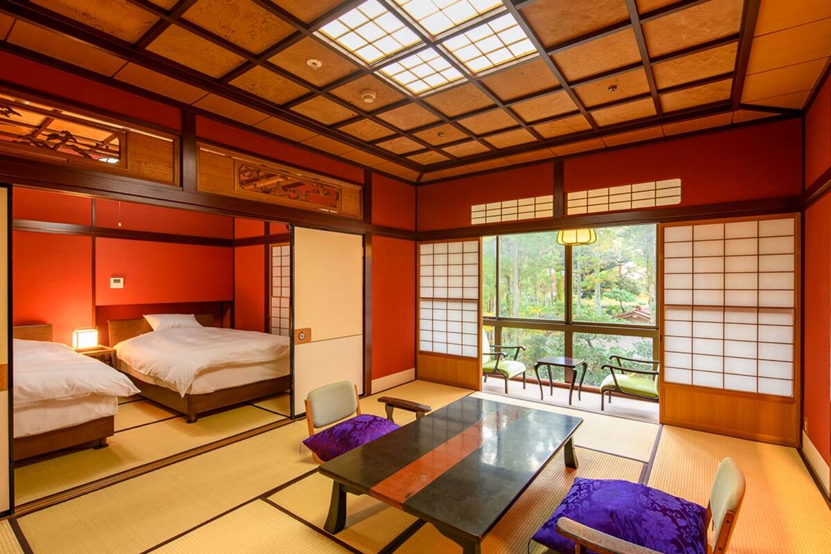 A traditional Japanese-style room with tatami flooring, two beds, a low table, and sliding doors.