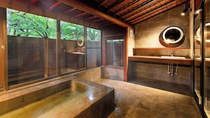 Un baño moderno con una bañera grande, un espejo redondo y un lavabo.