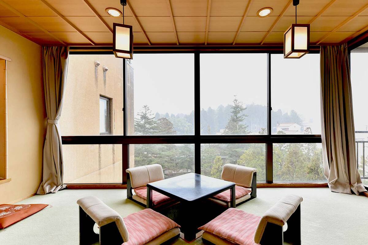 A room with a large window, a table, and four chairs.
