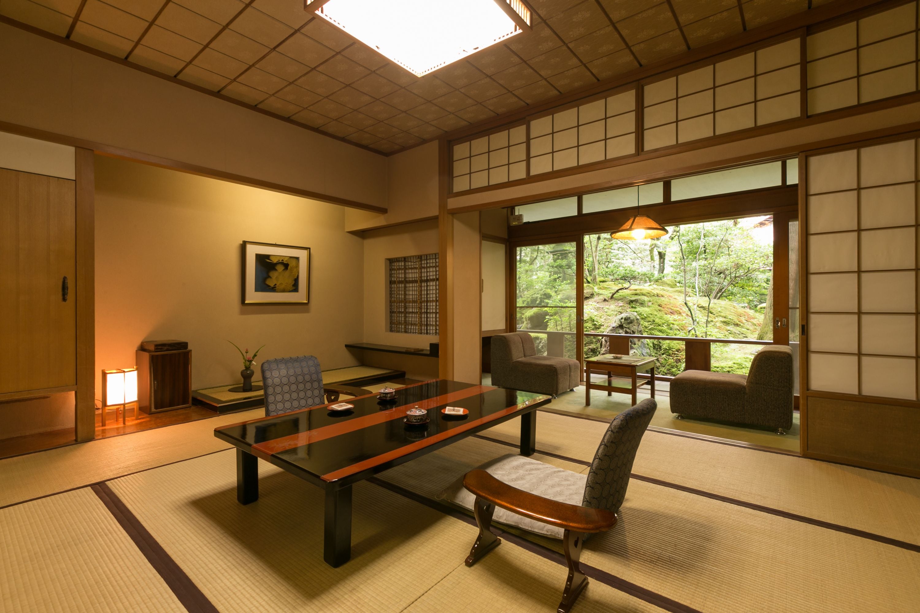 A traditional Japanese room with tatami flooring, a low table, and seating.