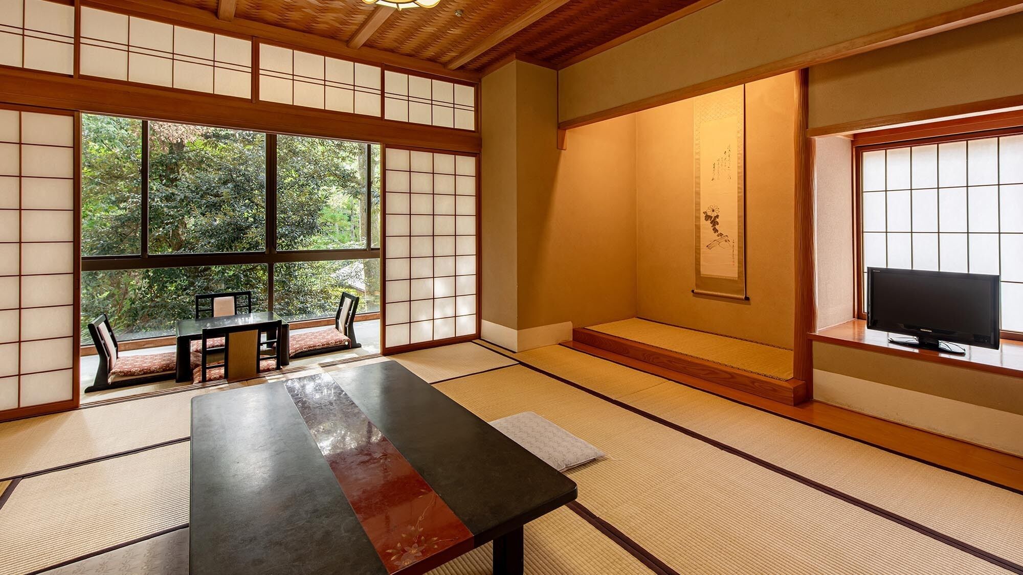 Una habitación japonesa tradicional con suelo de tatami, una mesa baja, un sofá y un televisor.