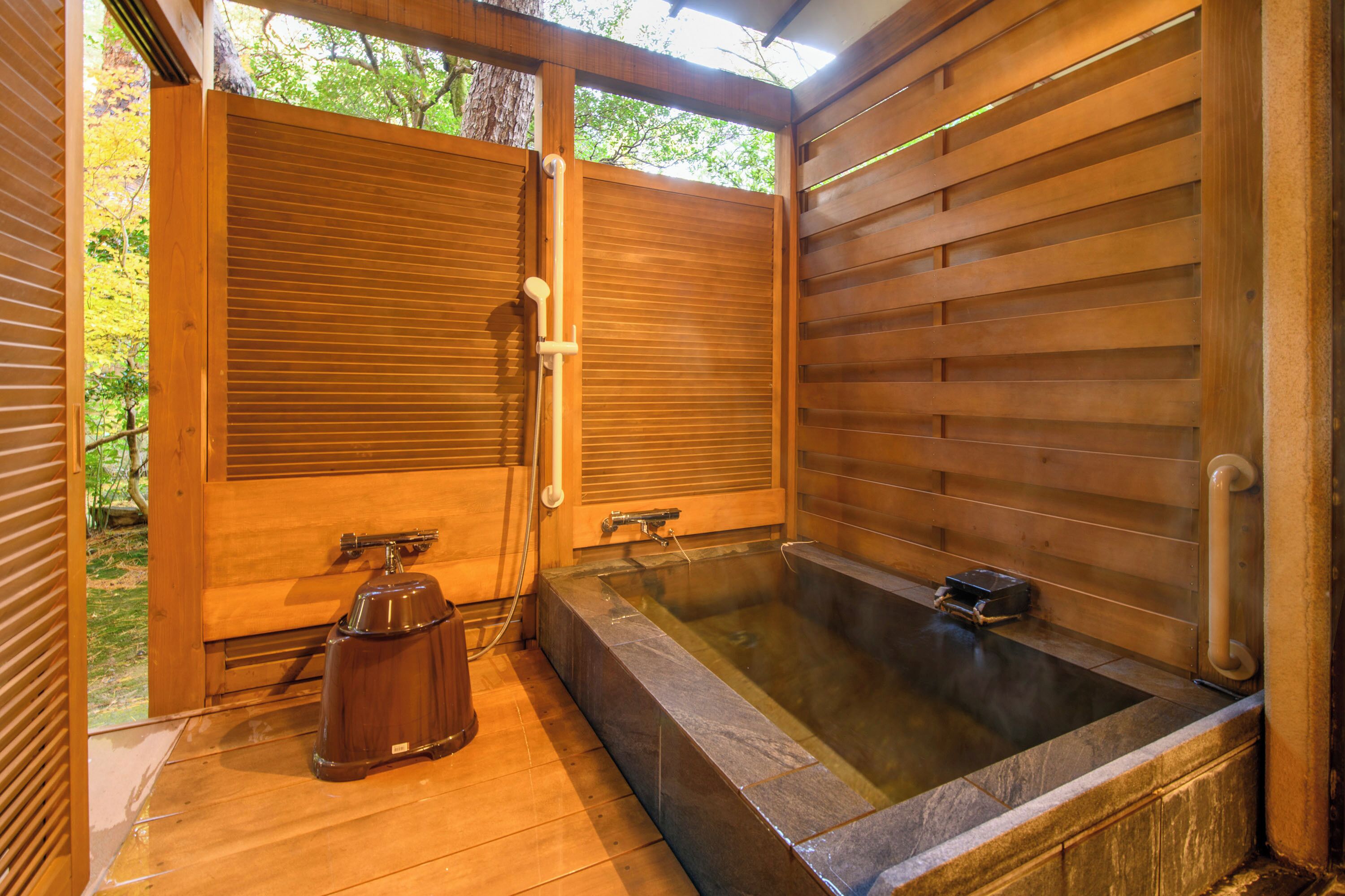 Een traditionele Japanse onsen met houten schuifdeuren, een stenen warmwaterbron en een houten vloer.