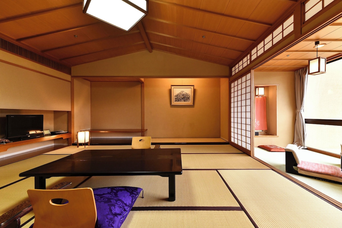 A traditional Japanese room with tatami flooring, a low table, a television, and a sliding door.