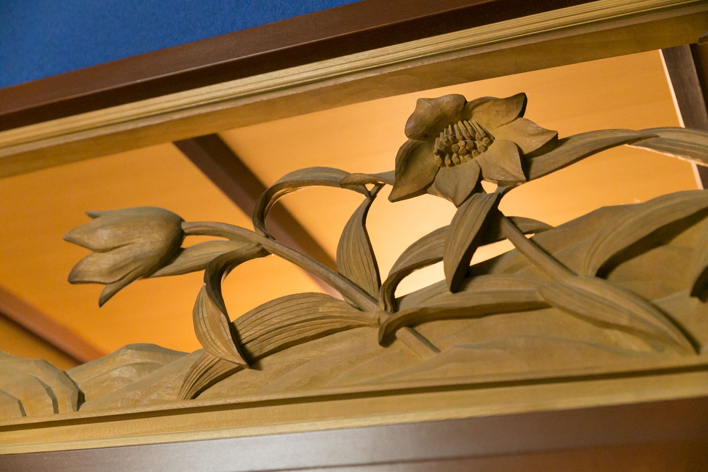 Eine Holzschnitzerei einer Blume mit Blättern und Stängeln.