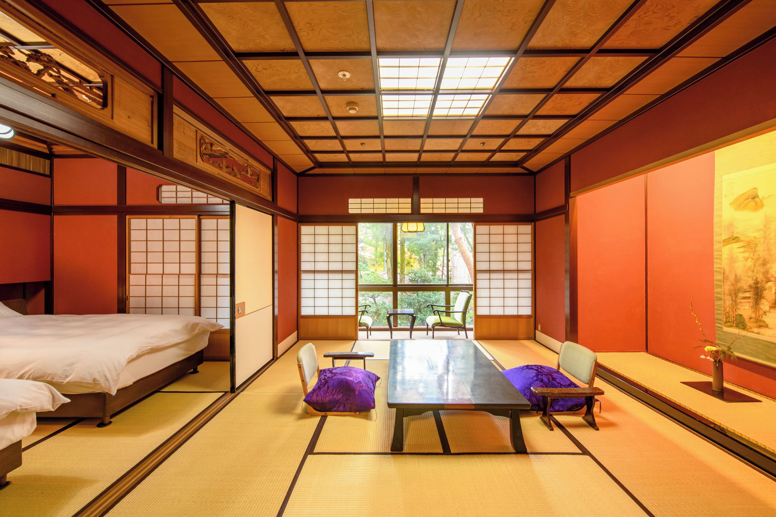 Una habitación japonesa tradicional con suelo de tatami, una mesa baja, sillas y una cama.