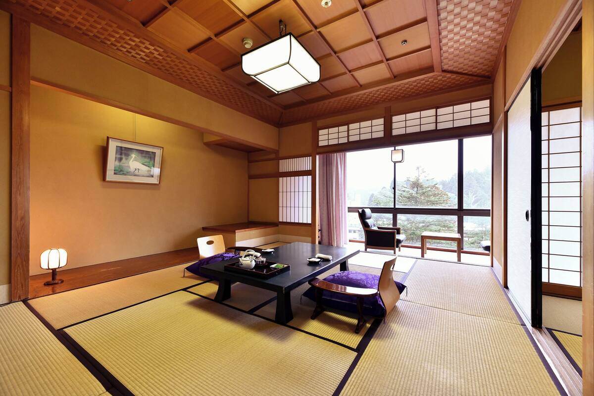 A traditional Japanese room with tatami flooring, a low table with tea set, and sliding doors leading to a balcony.