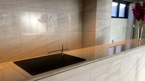 Une salle de bain moderne avec un lavabo en marbre, un plan de toilette noir et un vase rempli de fleurs.