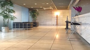 Un hall d’entrée spacieux, doté d’un comptoir de réception en marbre, de plantes en pot et d’une statue.