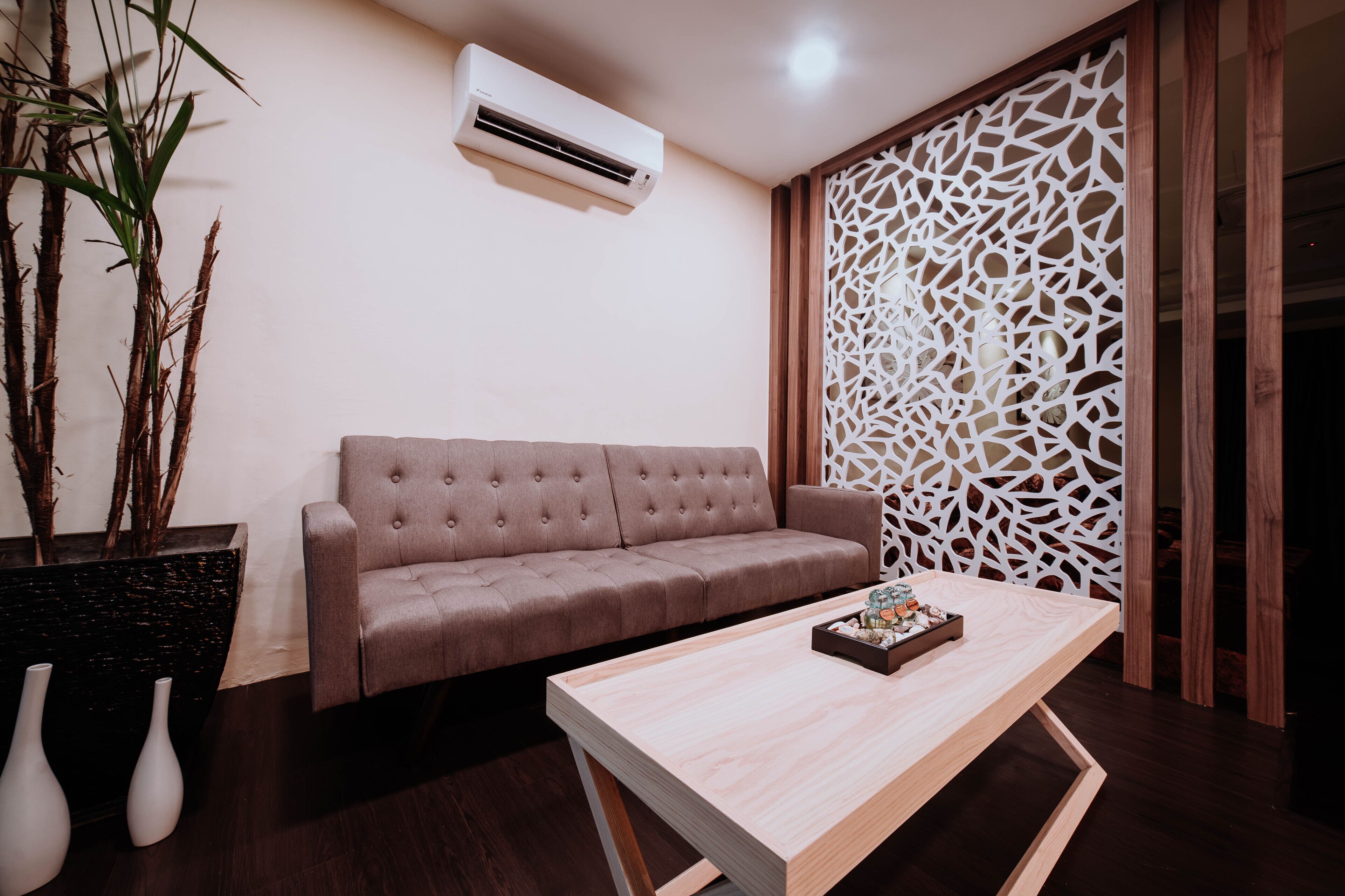 A modern living room with a beige sofa, a wooden coffee table, and a decorative white partition.