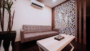 A modern living room with a beige sofa, a wooden coffee table, and a decorative white partition.
