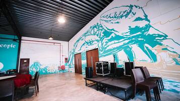A spacious room with a stage, chairs, and a large mural on the wall.