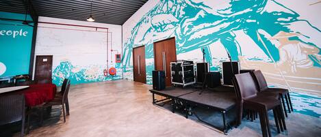 A spacious room with a stage, chairs, and a large mural on the wall.