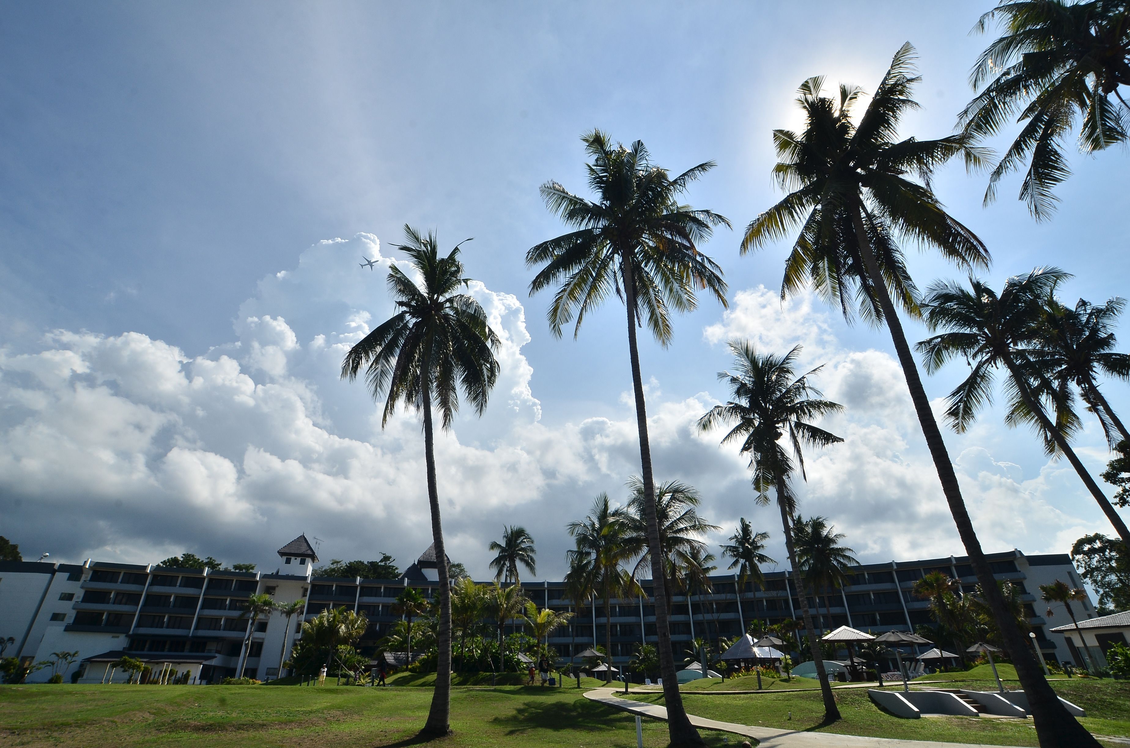 Ein Hotel mit mehreren Etagen, Palmen und blauem Himmel.