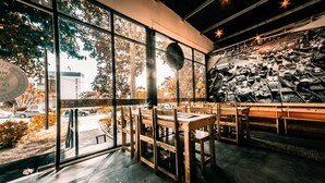 A restaurant with large windows, wooden tables, and a mural on the wall. - Tunamaya Beach & Spa Resort – Desaru (Bandar Penawar)
